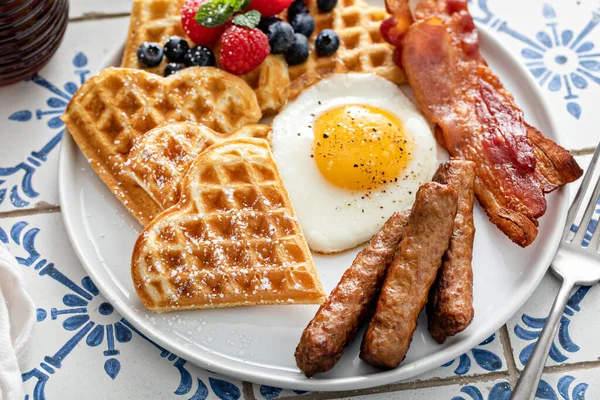 早餐桌上有华夫饼。煎蛋、咸肉和香肠 — 图库照片