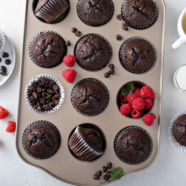 Schokoladenmuffins in einer Muffinpfanne mit Himbeeren — Stockfoto