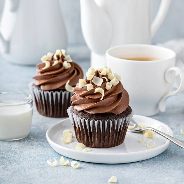 Тёмные шоколадные кексы со взбитыми глазурью и белыми шоколадными завитками — стоковое фото