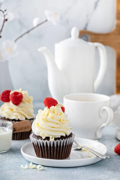 Шоколадные кексы с белой глазурью и малиной — стоковое фото