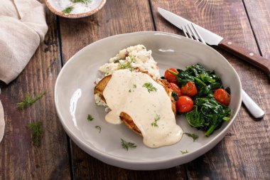 Kızarmış tavuk butları kremalı sos, sebze ve patates püresi ile servis edilir.