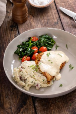 Kızarmış tavuk butları kremalı sos, sebze ve patates püresi ile servis edilir.