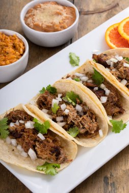 Meksika pilavı ve fasulyeli kişniş ve soğanlı domuz carnitas taco.