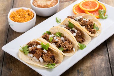 Meksika pilavı ve fasulyeli kişniş ve soğanlı domuz carnitas taco.