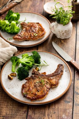 Grilled or pan fried pork chops on the bone with garlic and rosemary served with broccole for dinner