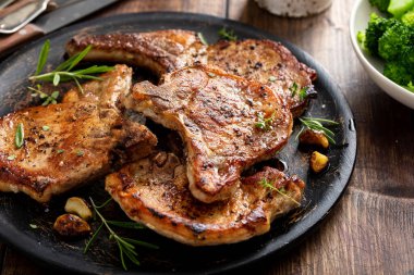 Grilled or pan fried pork chops on the bone with garlic and rosemary