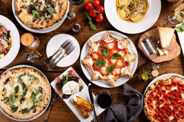 Masada çeşitli İtalyan yemekleri, pizza, makarna, peynir ve aperatifler.
