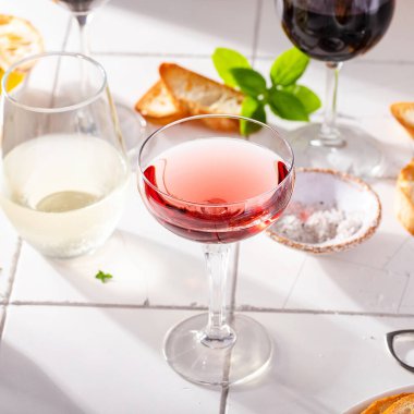 Şarap kadehlerinin çeşitleri kırmızı, beyaz ve gül şarabıyla kızarmış baget ve güneş ışığıyla birlikte zeytinyağı.