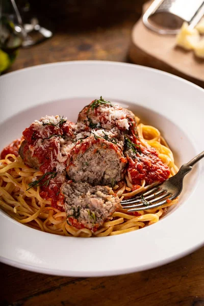 Spaghetti with meatballs and marinara sauce served with red wine on a wooden table