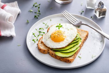 Avocado toast on a toasted multigrain bread with a fried egg on top