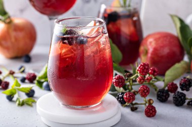 Fall berry and apple sangria in a glass with ice, refreshing fall cocktail or mocktail idea