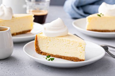 Classic New York cheesecake slice with graham cracker crust and a dollop of whipped cream