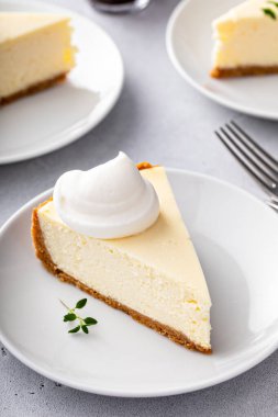 Classic New York cheesecake slice with graham cracker crust and a dollop of whipped cream