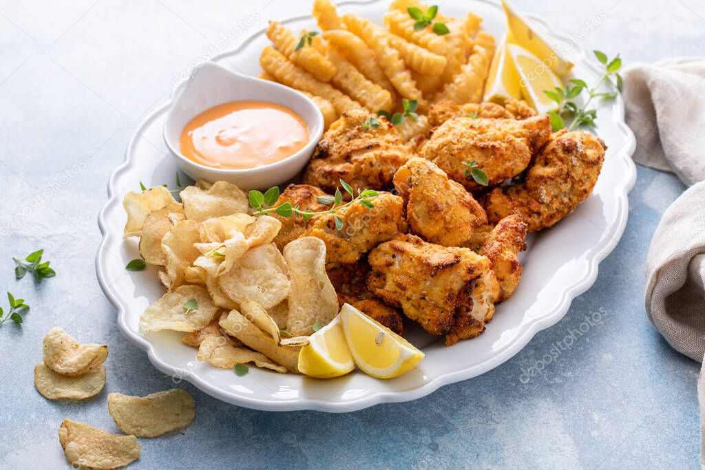 Fish and chips on a serving platter with catfish nuggets and creamy cocktail dipping sauce