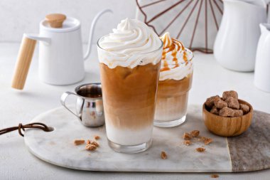 Iced caramel latte topped with whipped cream and caramel sauce, refreshing and sweet coffee drink