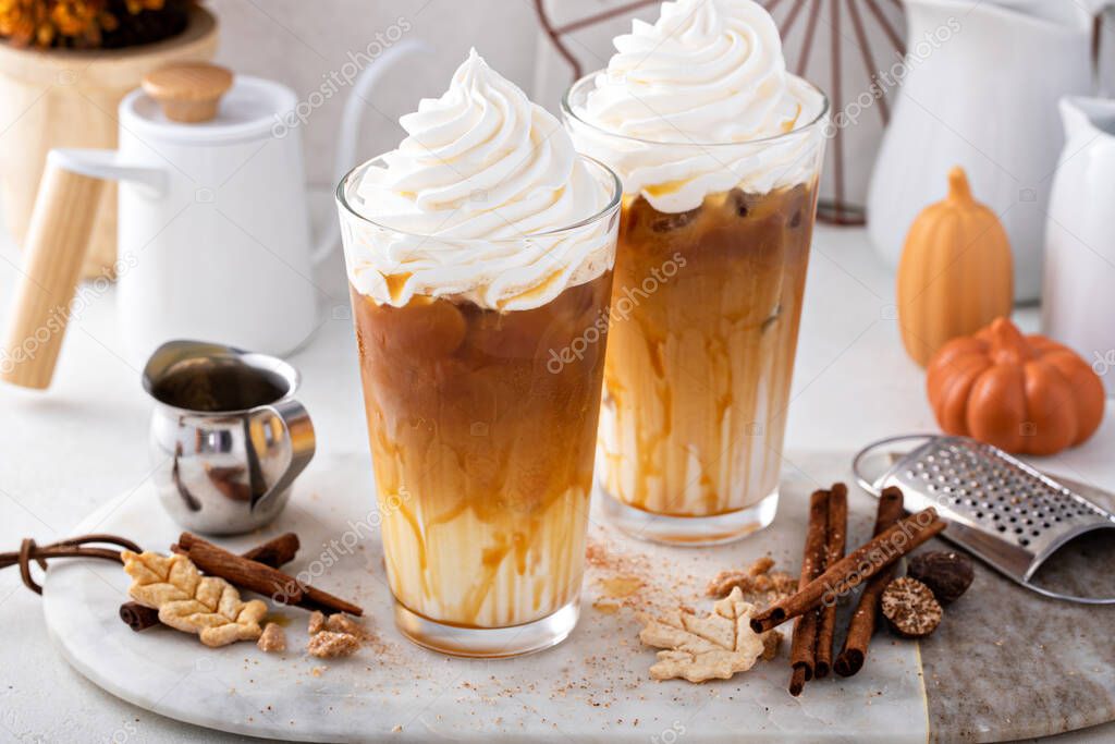 Iced pumpkin spice latte in tall glasses topped with whipped cream and caramel sauce