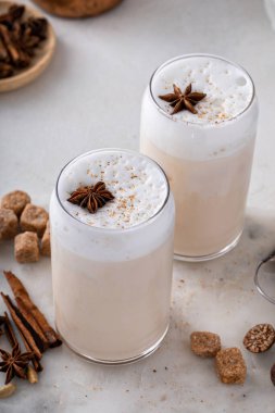 Iced chai latte with warm winter spices topped with milk foam, indian tea drink