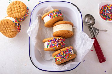 Vanilla ice cream sandwiches with peanut butter cookies covered in sprinkles overhead view