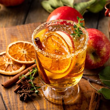 Festive fall cocktail or mocktail with hard cider, apple and orange with fall spices for Thanksgiving dinner