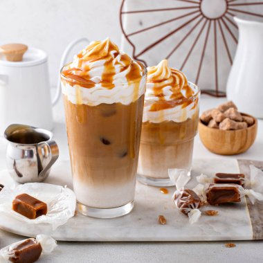 Iced caramel latte topped with whipped cream and caramel sauce, refreshing and sweet coffee drink
