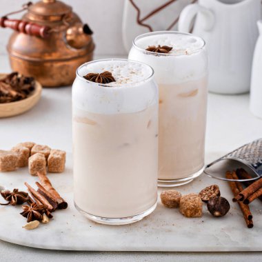 Iced chai latte with warm winter spices topped with milk foam, indian tea drink