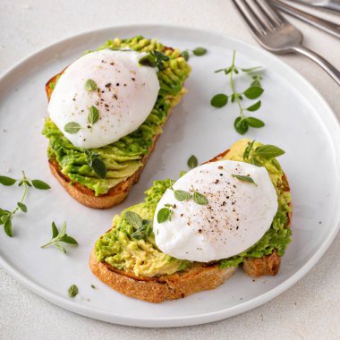 Avocado toast with a perfect poached egg on top with salt and pepper served with coffee for breakfast