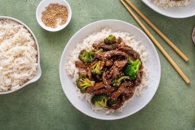 Beef and broccoli stir fry served over rice with sesame seeds top view