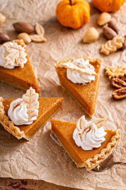 Festive pumpkin pie slices decorated with whipped cream and fall leaves