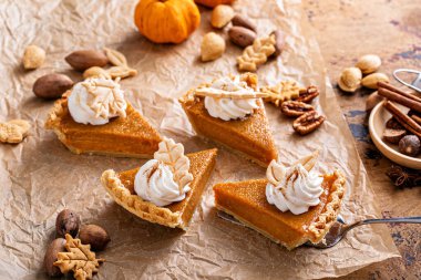 Festive pumpkin pie slices decorated with whipped cream and fall leaves