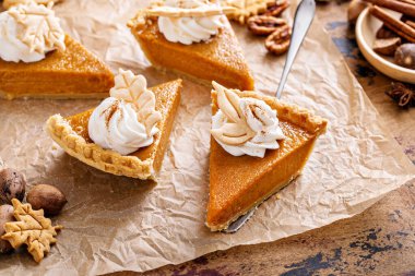 Festive pumpkin pie slices decorated with whipped cream and fall leaves