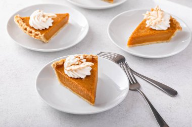 Slices of traditional pumpkin pie in a modern light and bright setting