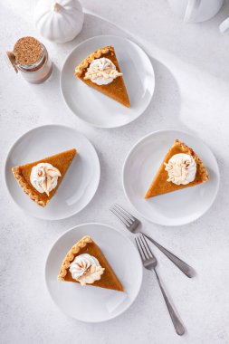 Slices of traditional pumpkin pie in a modern light and bright setting overhead view