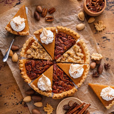 Traditional fall Thanksgiving pies variety of slices arranged into circle, pumpkin crumb and pecan pie overhead on a rustic wooden table