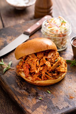 Pulled bbq chicken sandwich on a brioche bun served with cole slaw and bbq sauce
