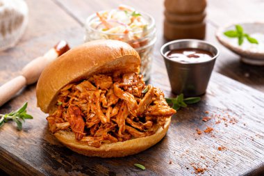 Pulled bbq chicken sandwich on a brioche bun served with cole slaw and bbq sauce