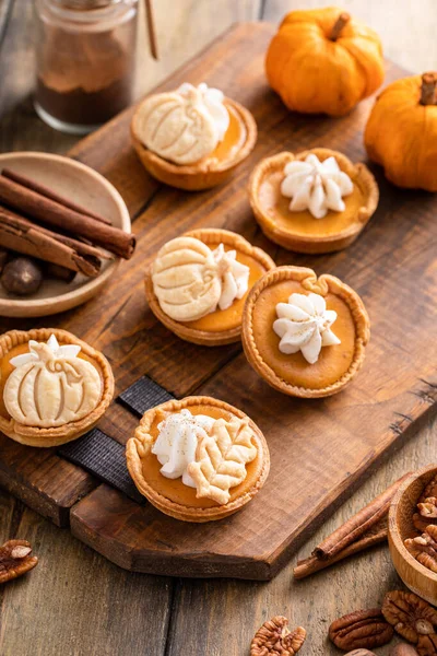 Mini pumpkin pies with wipped cream and spices baked in a muffin tin