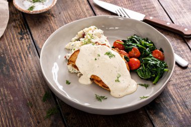 Roasted chicken thighs with dill pickle creamy sauce served with mashed potatoes and sauteed vegetables