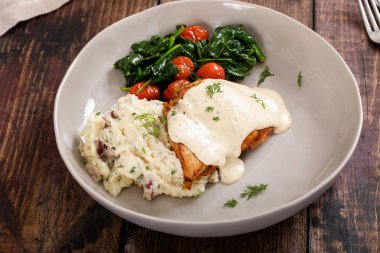 Roasted chicken thighs with dill pickle creamy sauce served with mashed potatoes and sauteed vegetables