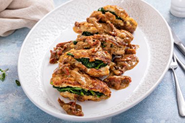 Spinach stuffed chicken on a serving platter with dried tomato sauce
