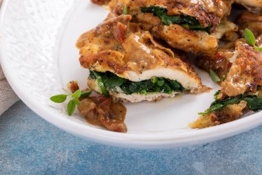 Spinach stuffed chicken on a serving platter with dried tomato sauce