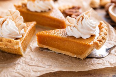 Festive pumpkin pie slices decorated with whipped cream and fall leaves clipart