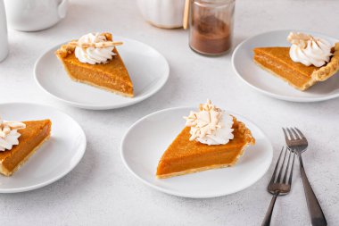 Slices of traditional pumpkin pie in a modern light and bright setting