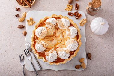 Pumpkin cheesecake swirl pie topped with whipped cream on a marble board, original Thanksgiving dessert idea