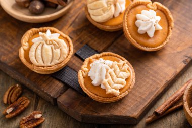 Mini pumpkin pies with wipped cream and spices baked in a muffin tin