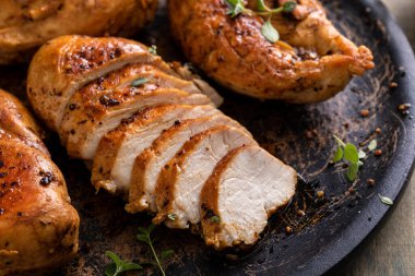 Roasted or seared chicken breast sliced on a plate with herbs and spices