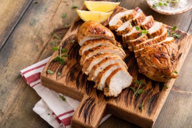 Roasted or seared chicken breast sliced on a cutting board with herbs and spices