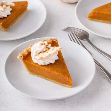 Slices of traditional pumpkin pie in a modern light and bright setting
