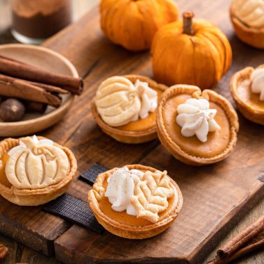 Mini pumpkin pies with wipped cream and spices baked in a muffin tin