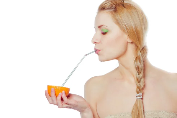 Schöne junge Frau trinkt Saft direkt aus einer Orangenfrucht — Stockfoto