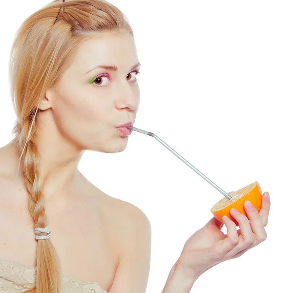 Vacker ung kvinna dricka juice direkt från en orange frukt — Stockfoto